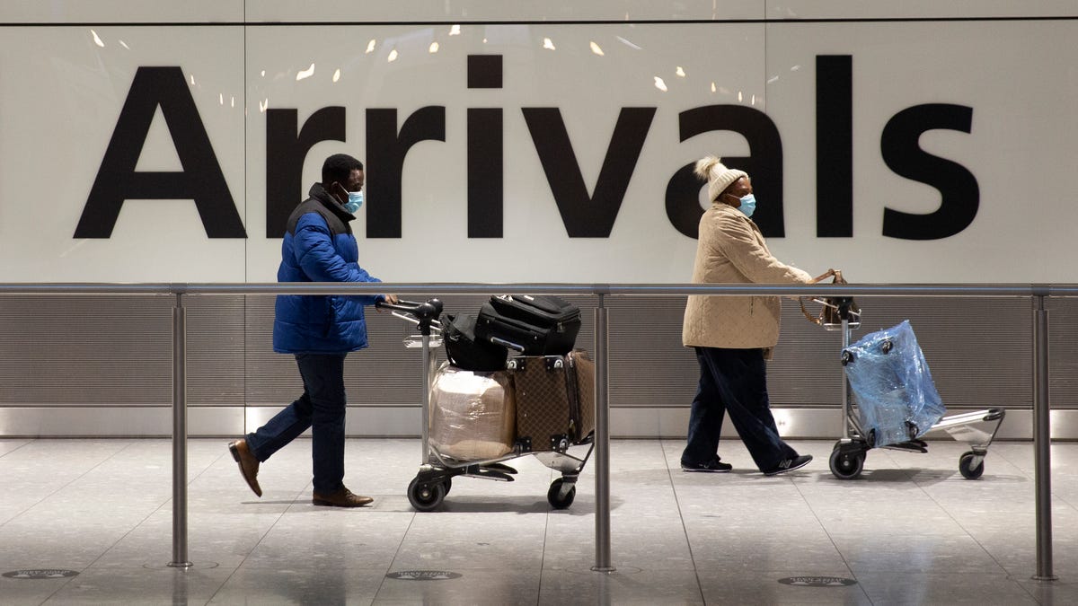 Arriving passengers walk past a sign in the arrivals area at Heathrow Airport in London Jan. 26, 2021, during England's third national lockdown since the coronavirus outbreak began. T