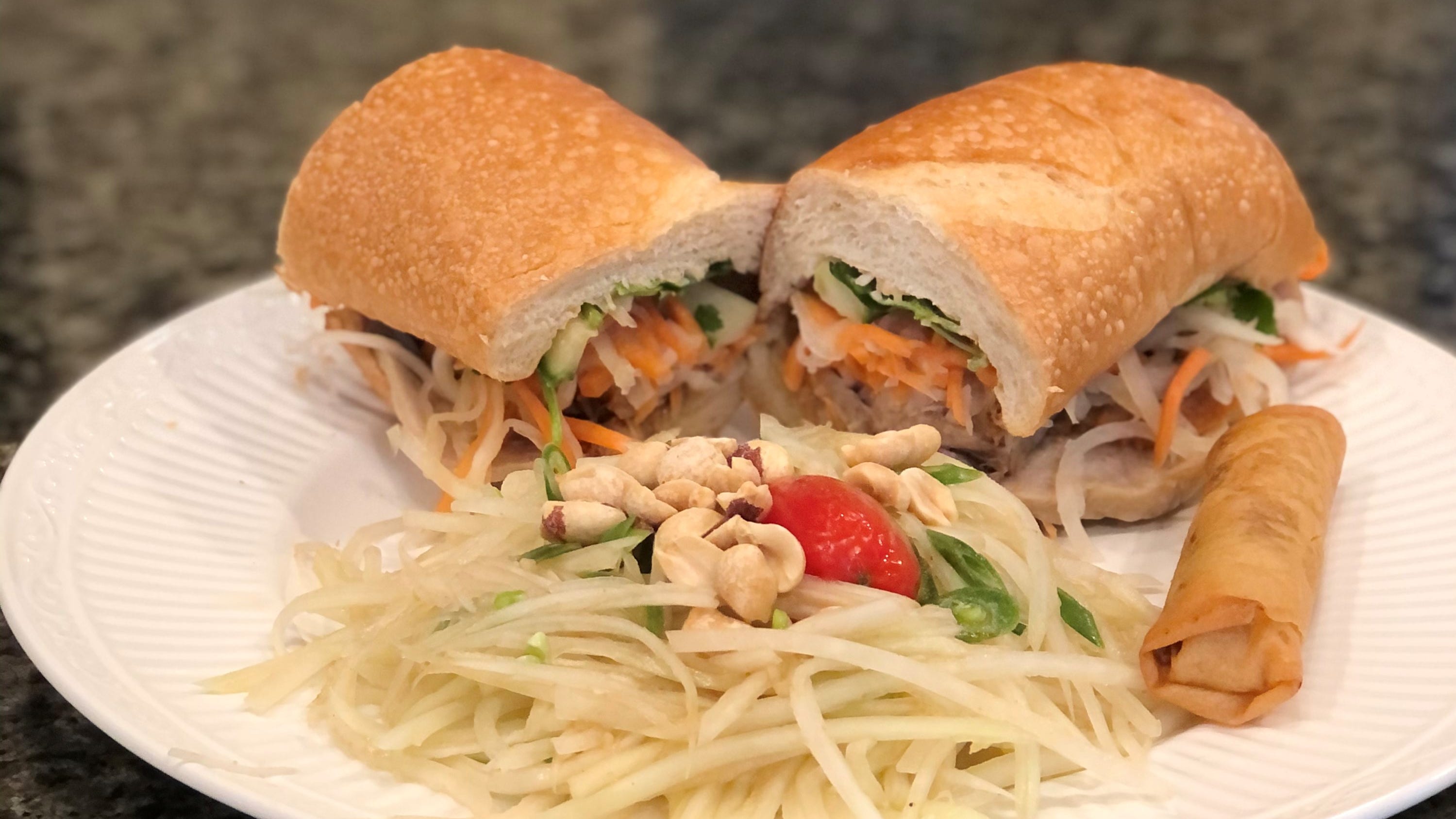 A dac biet banh mi sandwich, paired with a Vietnamese eggroll and papaya salad.