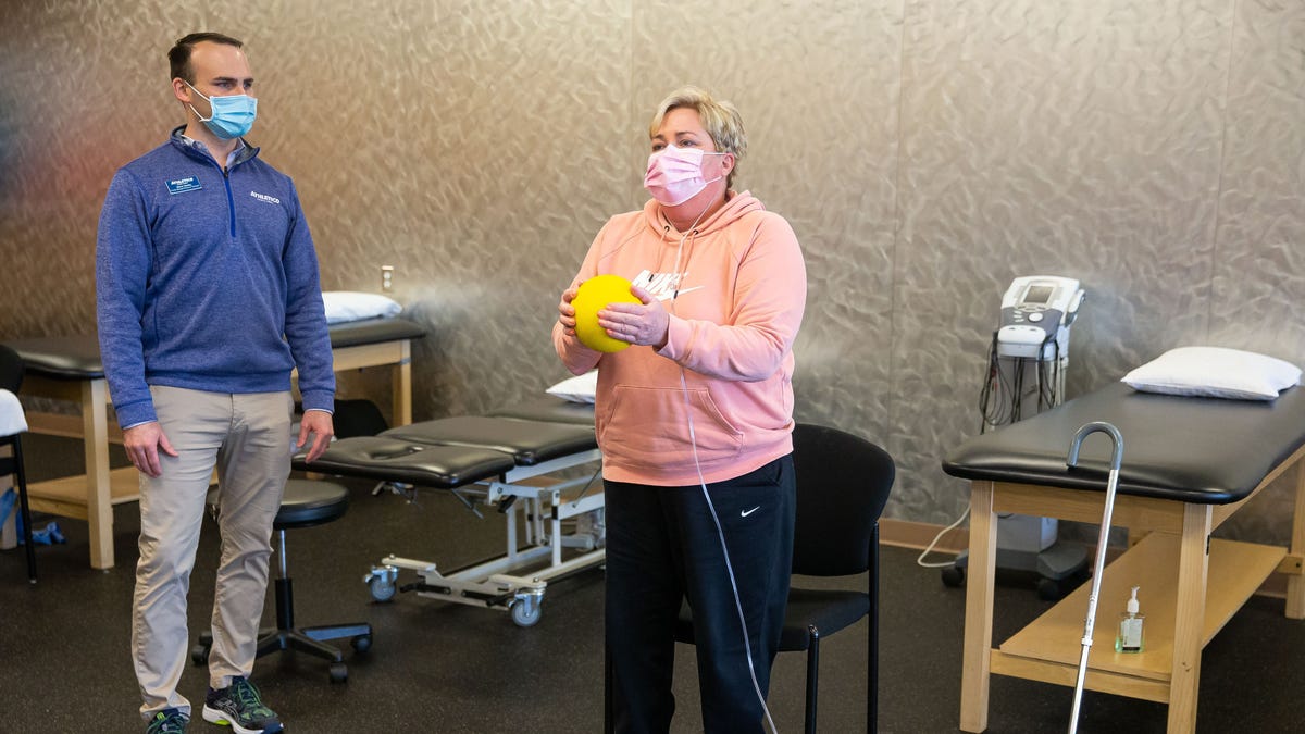 Deana Carlson performs an exercise of sitting and standing while tethered to oxygen as she goes through a physical therapy session under the watch of Steve Hanley, left, physical therapist at Athletico Physical Therapy, in Springfield, Ill., Thursday, February 11, 2021. Carlson is recovering from COVID-19 that kept her in Memorial Medical Center for 11 weeks and has since suffered from overall weakness, the need for oxygen because of damage to her lungs and persistent numbness in her right hand and arm. [Justin L. Fowler/The State Journal-Register]