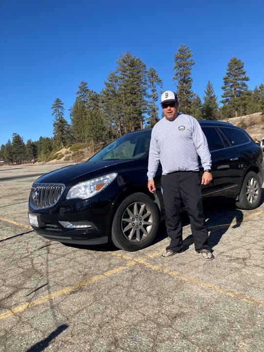 Tyler Arciaga of San Diego stands by the 2017 Buick Enclave he bought used in October 2020 because new vehicles were too expensive.