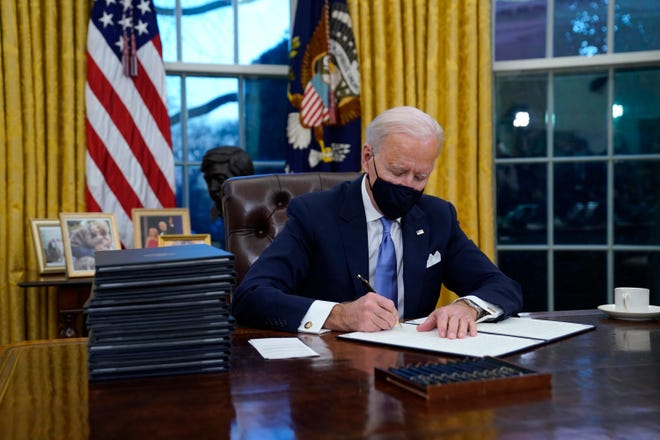 In this Jan. 20, 2021, file photo, President Joe Biden signs his first executive order in the Oval Office of the White House in Washington.