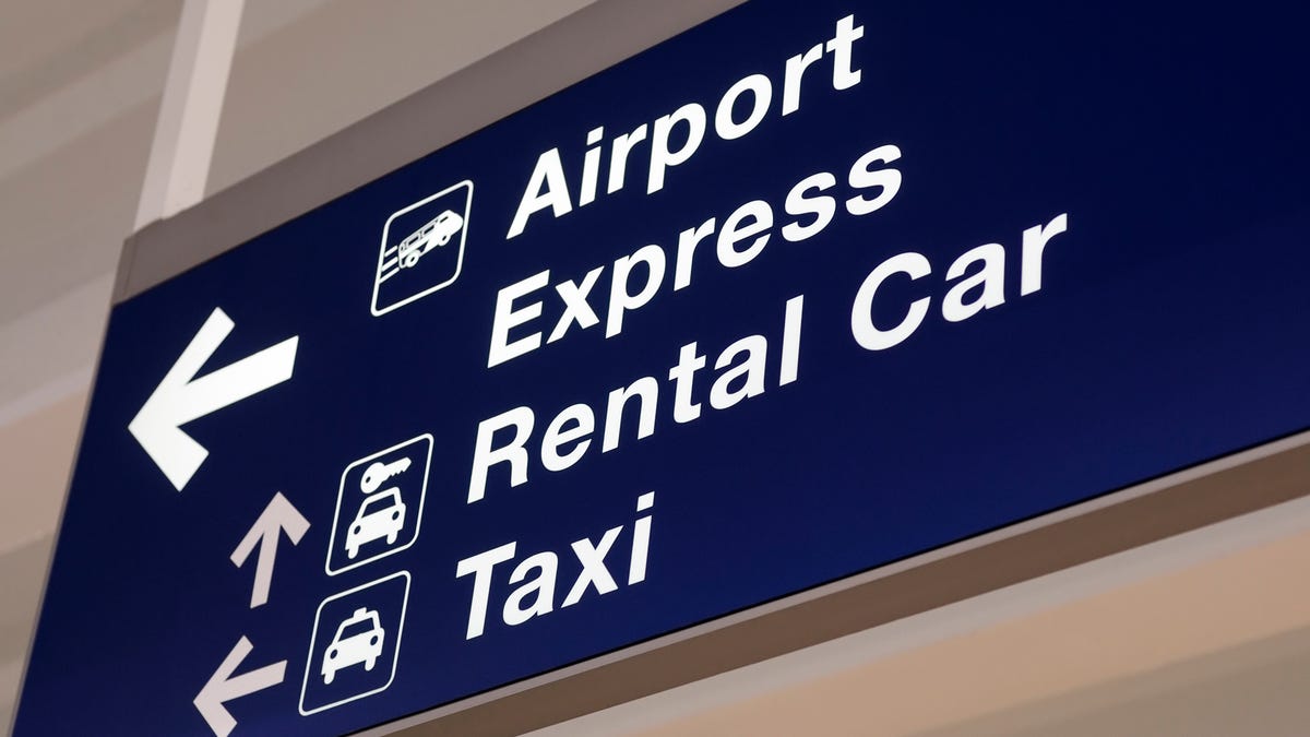 An airport sign with direction arrows for rental cars and taxis.