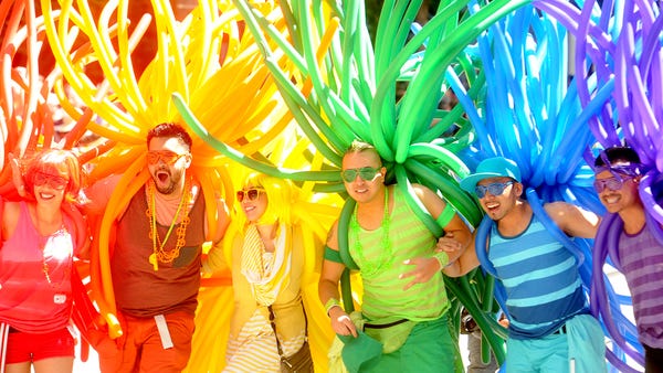 Revelers with balloons create a human rainbow duri