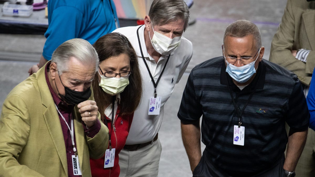 Wisconsin state Reps. Rachael Cabral-Guevara, second from left, and Chuck Wichgers, right, watch as Maricopa County ballots from the 2020 general election are examined and recounted by contractors hired by the Arizona Senate on June 12, 2021, at Veterans Memorial Coliseum, Phoenix, Arizona.