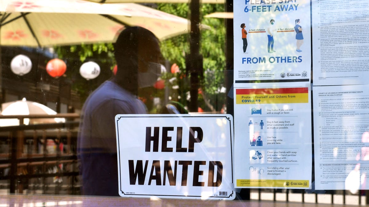 A "Help wanted" sign is posted beside coronavirus safety guidelines in front of a restaurant May 28 in Los Angeles.