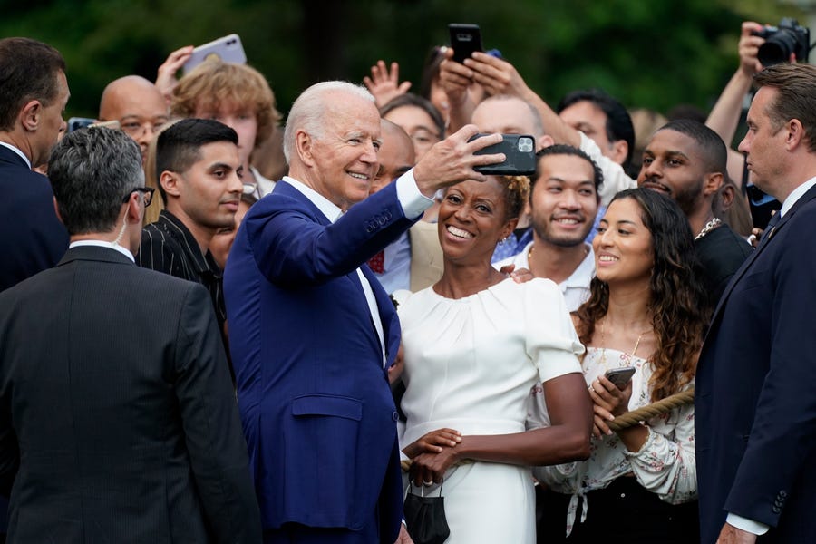 President Joe Biden poses for a photo with attendees during an Independence Day celebration.