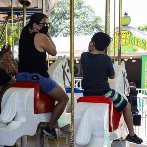 Visitors wearing protective masks ride on the caro