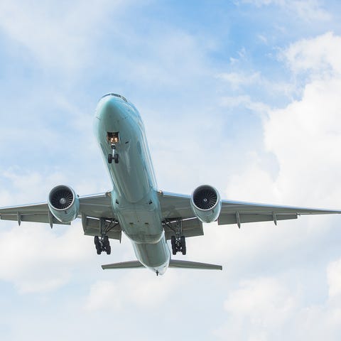 Boeing 777 flying in partly cloudy sky