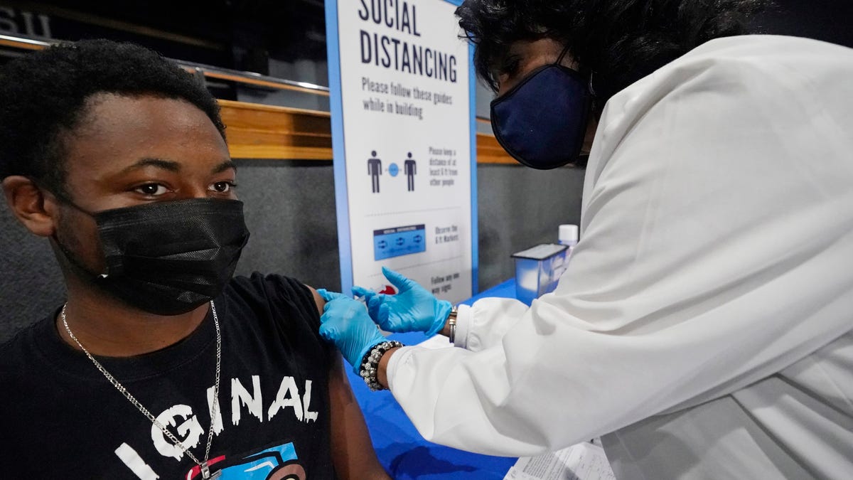 Eric Wilson, 20, whose father recently died of COVID-19, receives a dose of the Moderna vaccine on Tuesday in the Rose E. McCoy Auditorium at Jackson State University in Jackson, Miss.