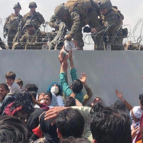 US Marine grabs an infant over a fence of barbed w