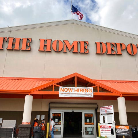 A "Now Hiring," sign hangs over the entrance of Th