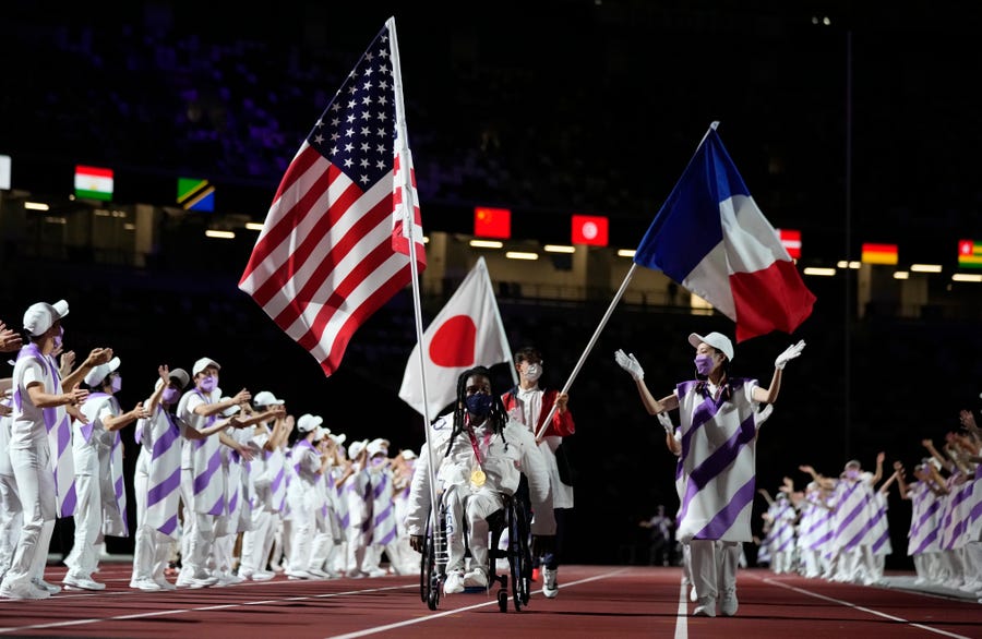 Flag bearers for Team USA, Japan and France enter the stadium during the closing ceremony for the 2020 Paralympics.