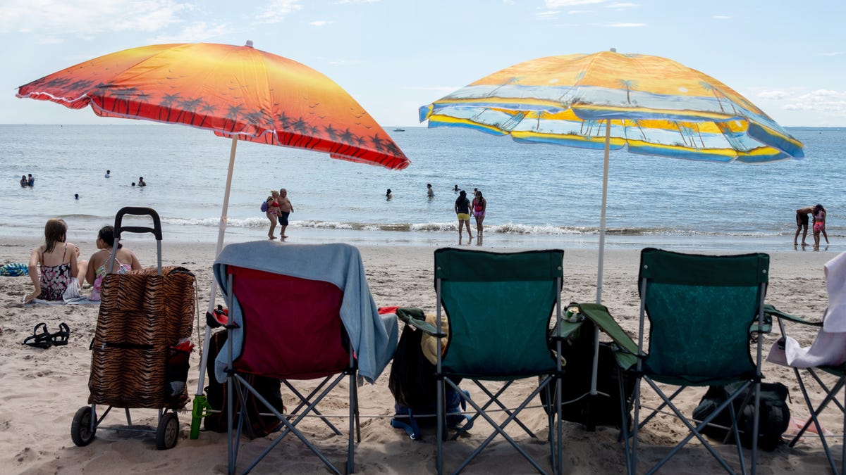 People walk along the water near empty beach chairs at Coney Island over Labor Day Weekend on September 4, 2021 in the Brooklyn Borough of New York City.