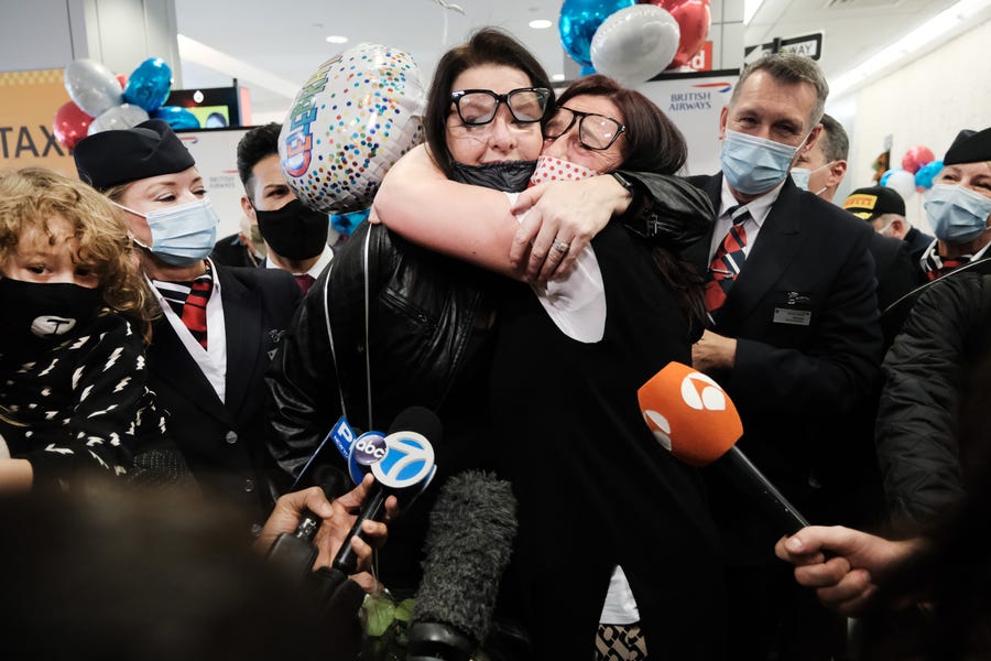 NEW YORK CITY - NOVEMBER 08: Jill Chambers (R) of Manchester, England is reunited with her sister Louise as passengers arrive from the first British Airways flight to arrive since the U.S. lifted pandemic travel restrictions on November 08, 2021 in New York City. International visitors will have to follow new rules, such as vaccination requirements. (Photo by Spencer Platt/Getty Images)