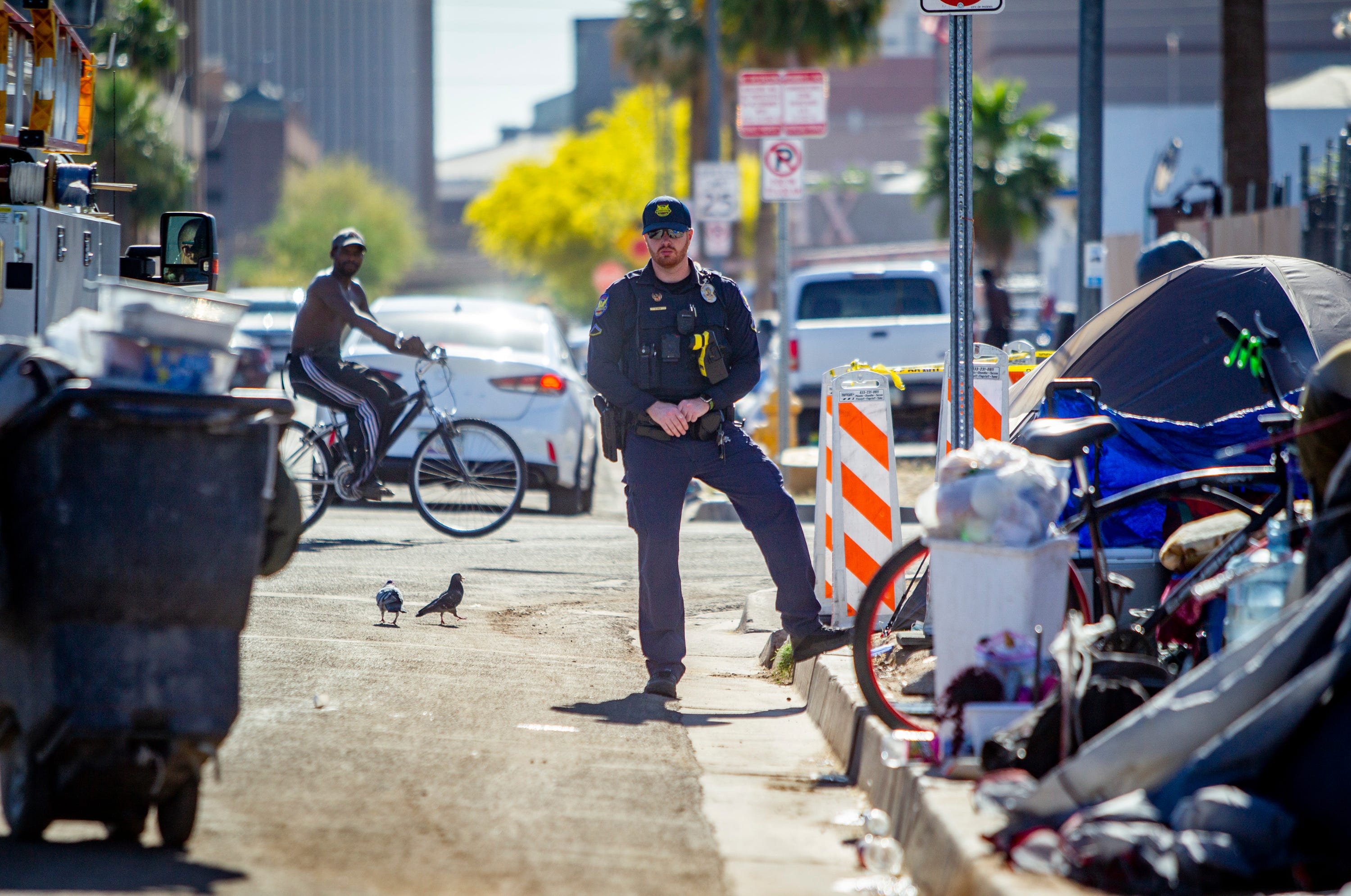 A Phoenix police officer keeps watch during a clean up of a homeless encampment in Phoenix on April 29, 2020.