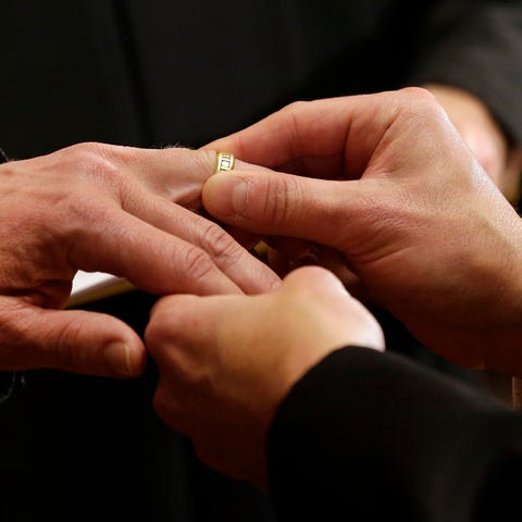 Thomas Rabe, right, places a wedding ring on Rober