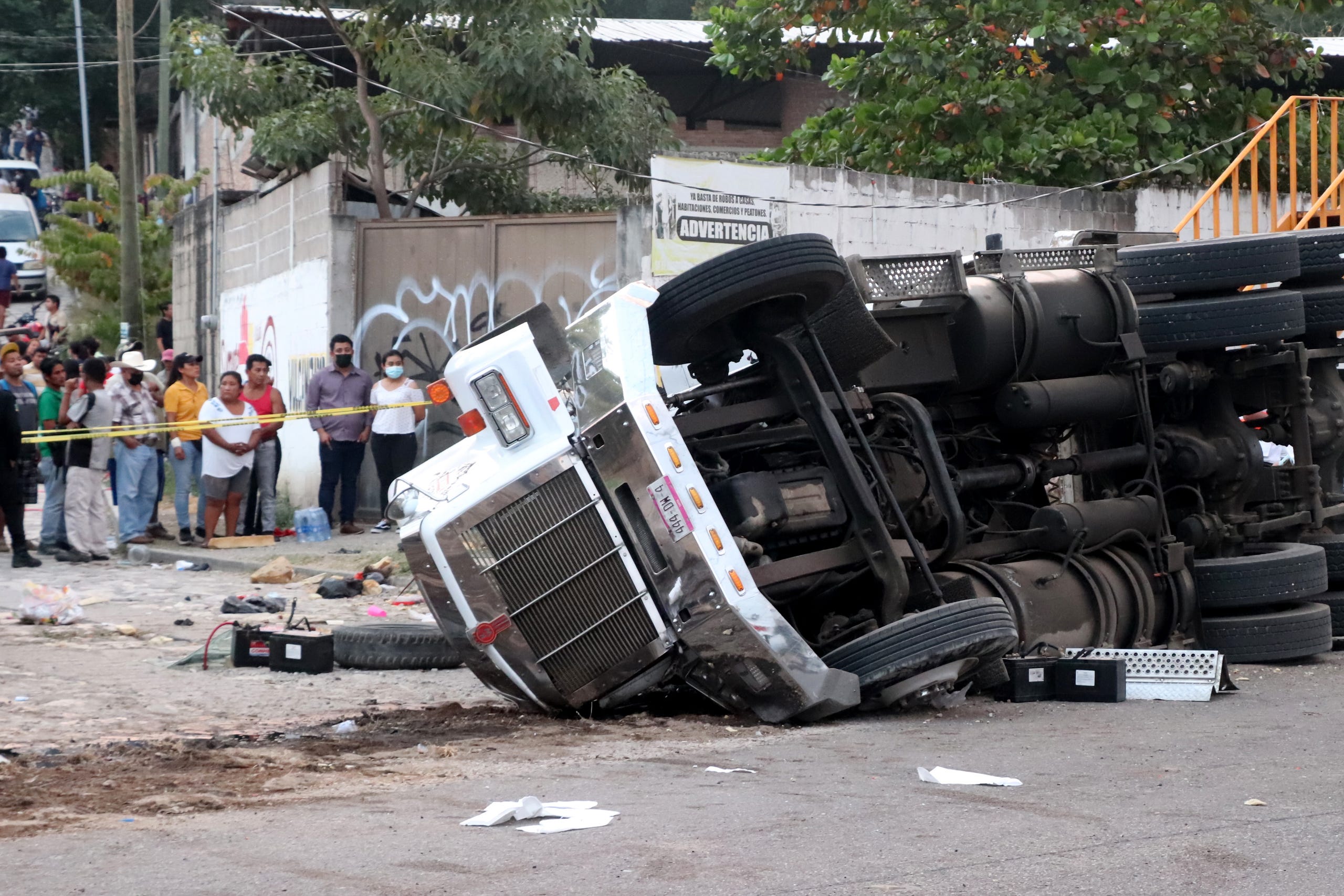 People observe a truck that rolled over after a traffic accident that was transporting migrants from Central America on December 9, 2021 in Tuxtla Gutierrez, Mexico.