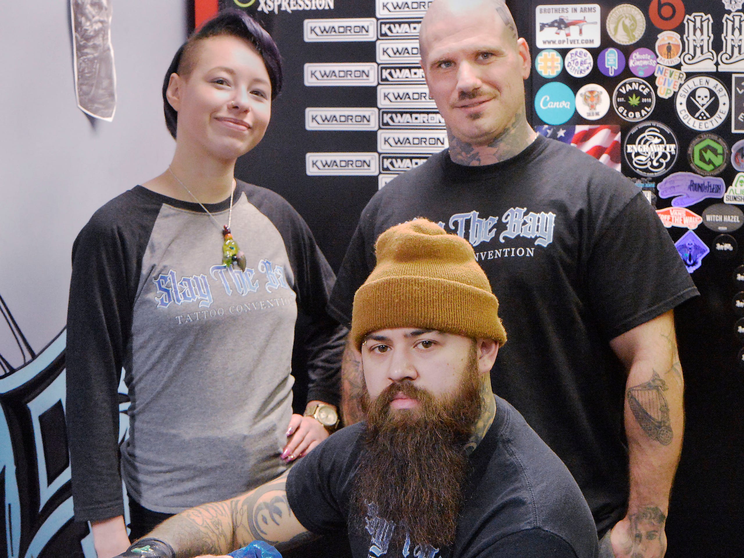 Symone Crockett, 27, left, joins Slay the Bay tattoo event coordinators and tattoo artists Garrett Ybanez, 30, center, and Ryan Quinn, 32, on Dec. 14, 2021, at InkXpression tattoo shop in Millcreek Township.