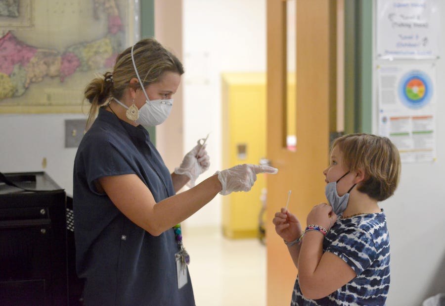 Harwich Elementary School nurse Holly Tavano helps her daughter, Linnea, 10, with a coronavirus test Dec. 6. Students at the school in Massachusetts have access to testing that lets them stay in school if they've had a COVID-19 exposure. In-person school could be in jeopardy across the nation as the omicron variant arrives.    