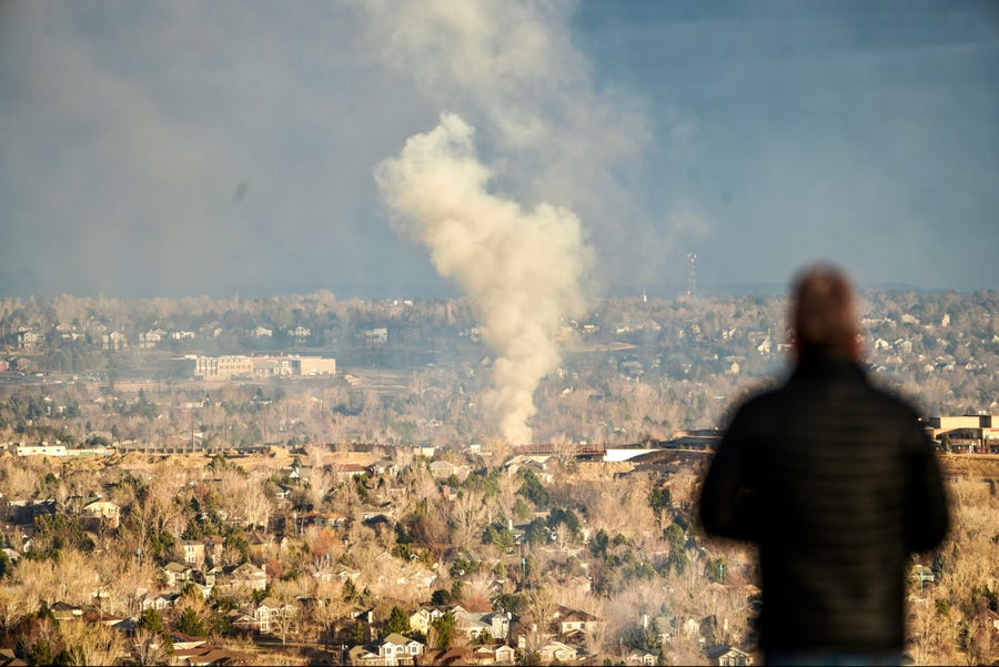 A person watches a smoke plume rise over Superior, Colorado, on Friday morning after a devastating wildfire destroyed hundreds of homes in the area.