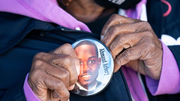 Annie Polite puts on a button for Ahmaud Arbery ou