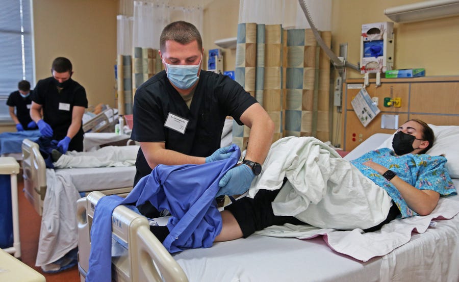 Wisconsin National Guard 2nd Lt. Christopher Kuechenmeister trains in patient dressing on SPC Kasey Carter at Madison College on Wednesday, Jan. 19, 2022. They were training for their Certified Nursing Assistant certification in an effort to help support Wisconsinâ€™s hospitals and nursing homes that have been strained during the pandemic.    