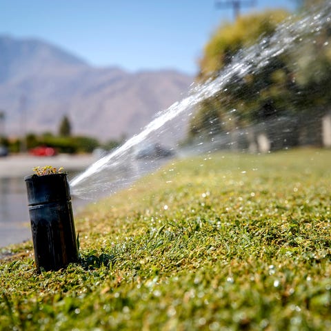 Sprinklers spray water on a lawn in Palm Springs o