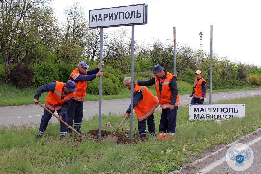 This handout picture taken and released by the Donetsk People Republic Ministry of transport on May 5, 2022 shows municipal workers changed Ukrainian road signs to Russian outside the city of Mariupol.