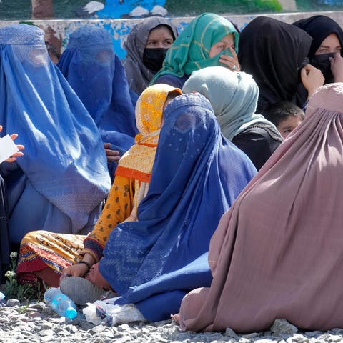 Afghan women wait to receive food rations distribu