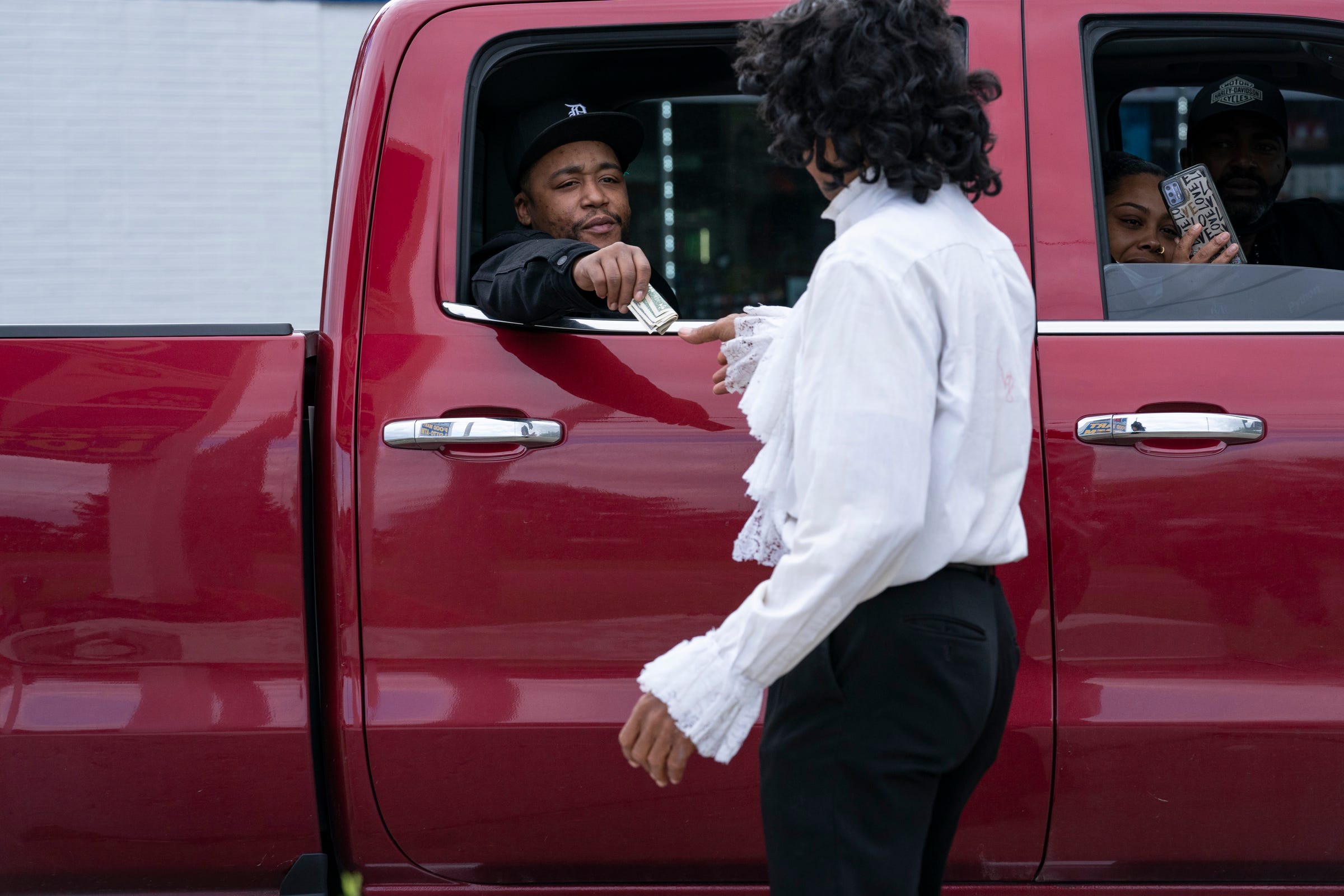 Michael Jackson impersonator Calvin Nelson, 65, of Detroit, gets a tip from Jim Mann of Detroit, as he performs in front of a gas station at the corner of Eight Mile and Sorrento Avenue in Detroit Saturday, Oct. 16, 2021. 