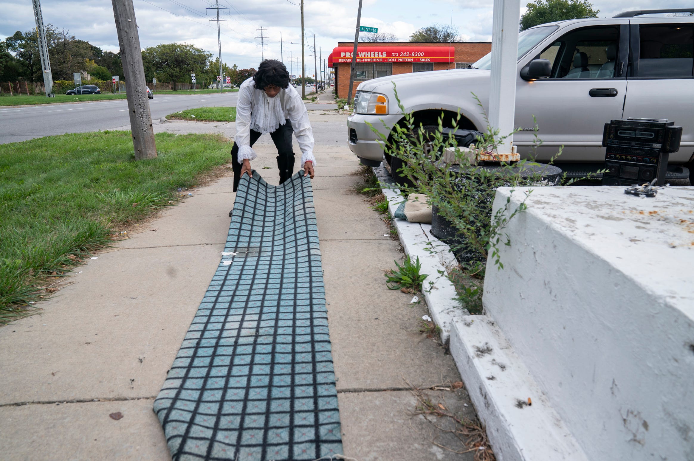 Michael Jackson impersonator Calvin Nelson, 65, of Detroit, lays down some strips of carpet before he impersonates the late artist by playing his music and performing Michael Jackson's signature dance moves at the corner of Eight Mile Road and Sorrento Avenue in Detroit Saturday, Oct. 16, 2021.