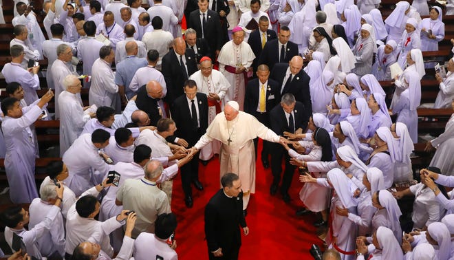 Priests, theologians and educators touch the hands of Pope Francis as he departs after their meeting at Saint Peter's Parish on the outskirts of Bangkok, Thailand, in November 2019.
