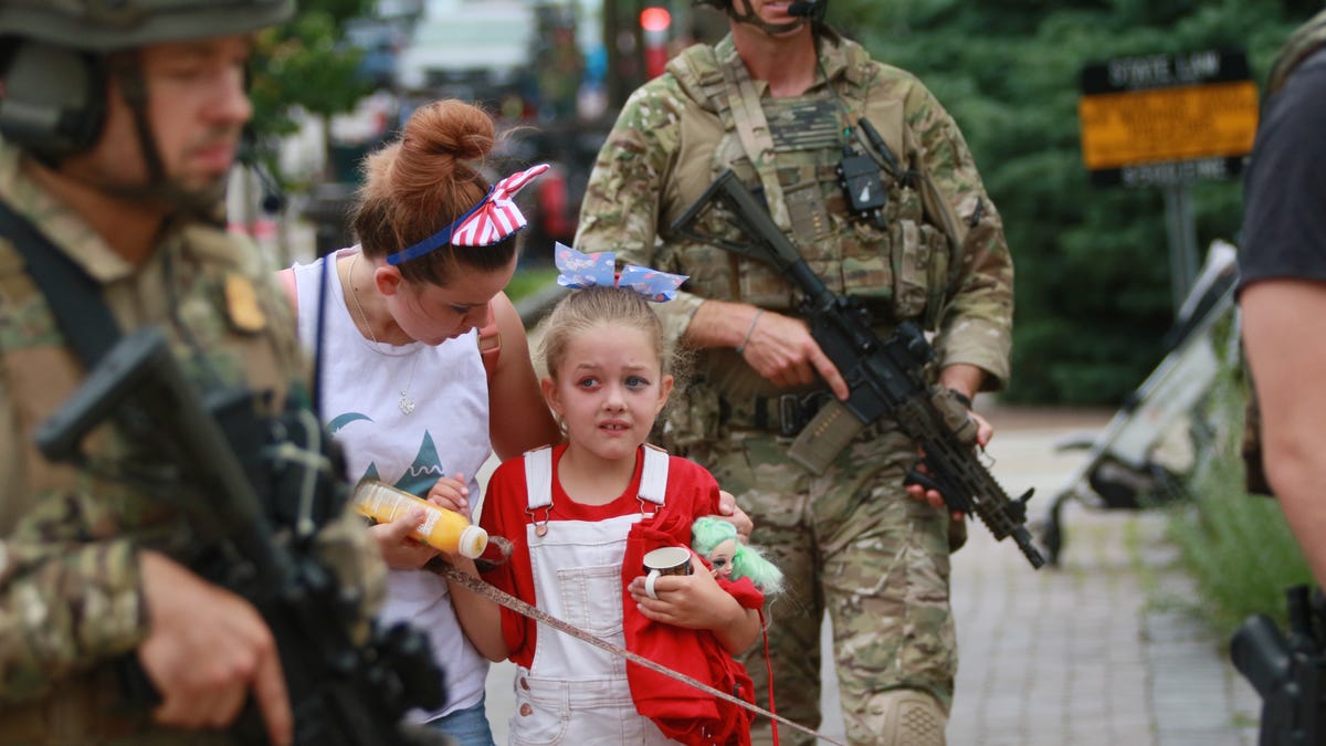 Law enforcement escorts a family away from the scene of a shooting at a Fourth of July parade on July 4, 2022 in Highland Park, Ill.