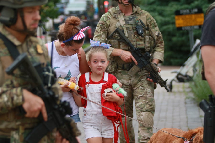 Law enforcement escorts a family away from the scene of a shooting at a Fourth of July parade on July 4, 2022 in Highland Park, Illinois. Police have detained Robert 