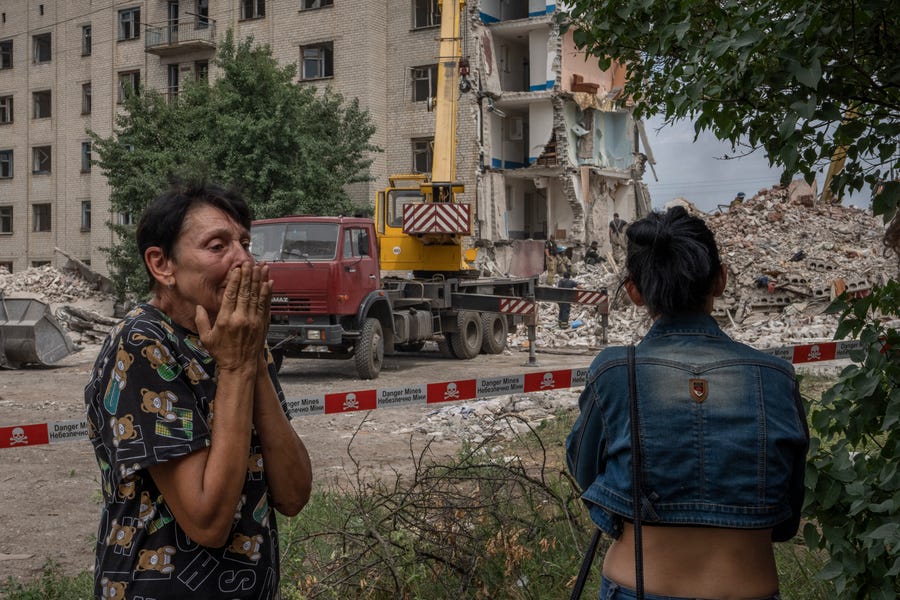 Iryna Shulimova, 59, weeps at the scene in the aftermath of a Russian rocket that hit an apartment residential block, in Chasiv Yar, Donetsk region, eastern Ukraine, Sunday, July 10, 2022. At least 15 people were killed and more than 20 people may still be trapped in the rubble, officials said Sunday.