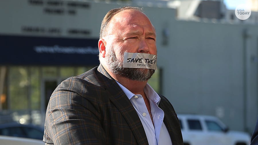 Alex Jones arrives at the Travis County Courthouse Tuesday, July 26, 2022, with a piece of tape over his mouth that reads 