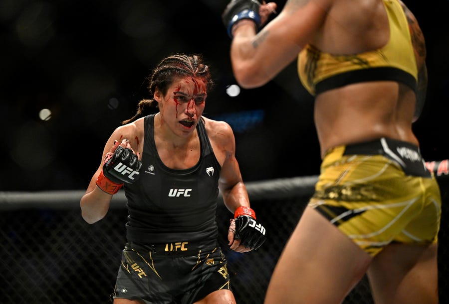 Julianna Pena fights Amanda Nunes (blue gloves) in a women's bantamweight title bout during UFC 277.