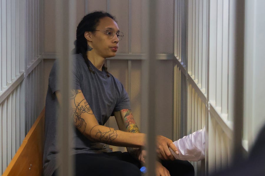 WNBA star and two-time Olympic gold medalist Brittney Griner shakes hands with her laywer as she listens a verdict standing in a cage in a courtroom in Khimki just outside Moscow, Russia,  Aug. 4, 2022. A judge in Russia has convicted American basketball star Brittney Griner of drug possession and smuggling and sentenced her to nine years in prison.