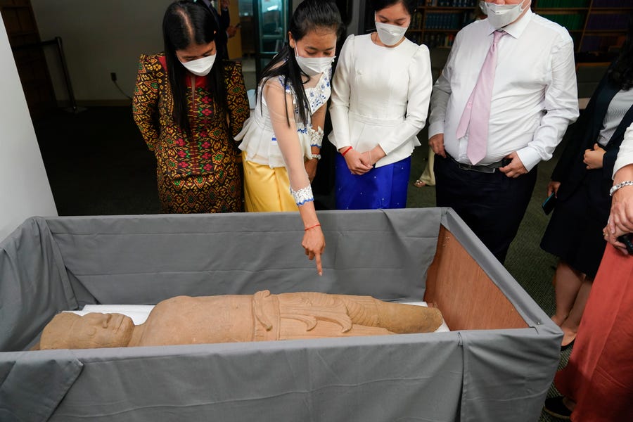 People look at some of the Cambodian antiquities recovered by the United States Attorney's Office after a news conference in New York, Monday, Aug. 8, 2022. Officials announced the repatriation of 30 antiquities to Cambodia that had been illegally trafficked. (AP Photo/Seth Wenig)