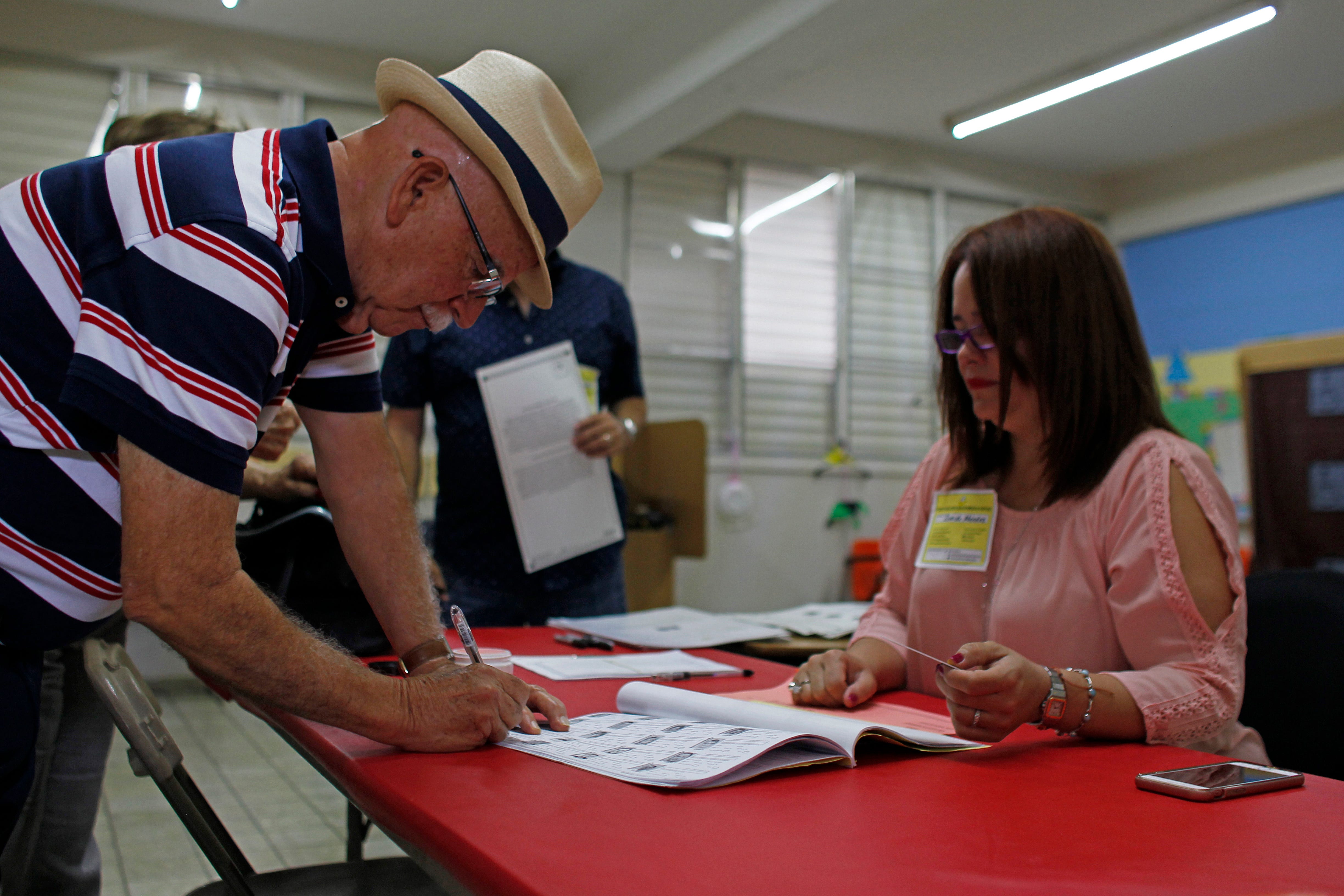 Un hombre firma una lista electoral antes de emitir su voto en el referéndum sobre el estatus político de Puerto Rico en un colegio electoral en Guaynabo el 11 de junio de 2017.