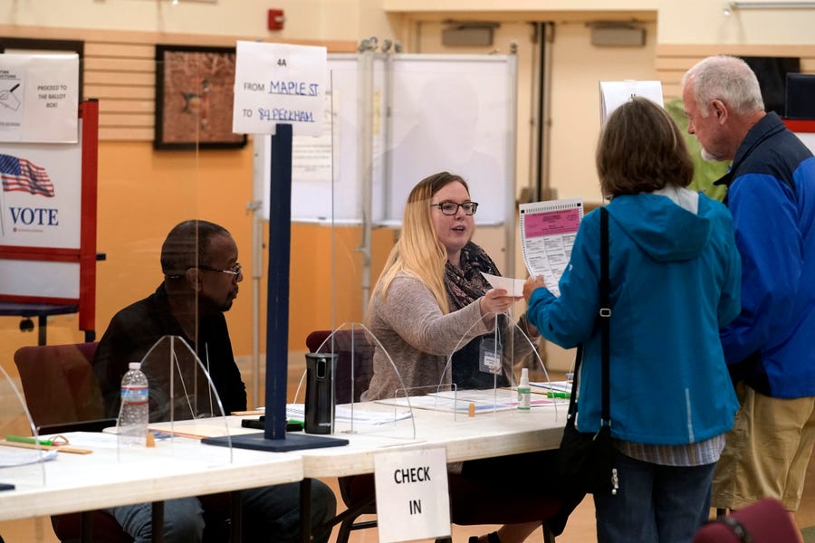 An election worker, center, assists voters, right, in the Massachusetts primary election at a polling place, Tuesday, Sept. 6, 2022, in Attleboro, Massachusetts.