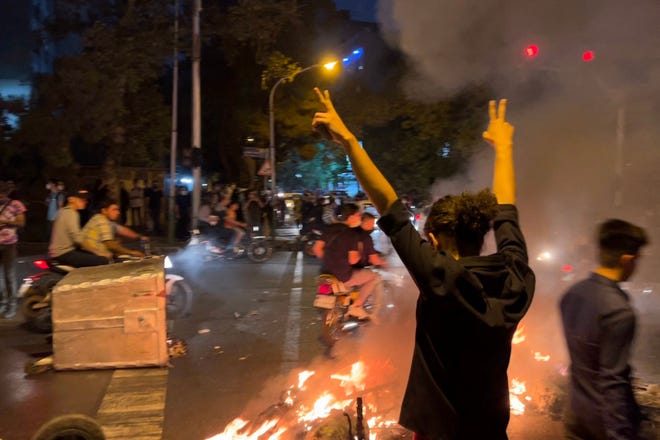 A demonstrator raises his arms and makes the victory sign during a protest for Mahsa Amini, a woman who died after being arrested by the Islamic republic's "morality police", in Tehran on September 19, 2022.