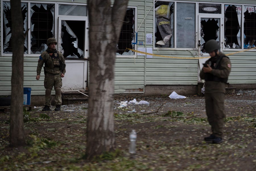 Ukrainian servicemen stand on the site of a Russian attack in Zaporizhzhia, Ukraine, Friday, Sept. 30, 2022.