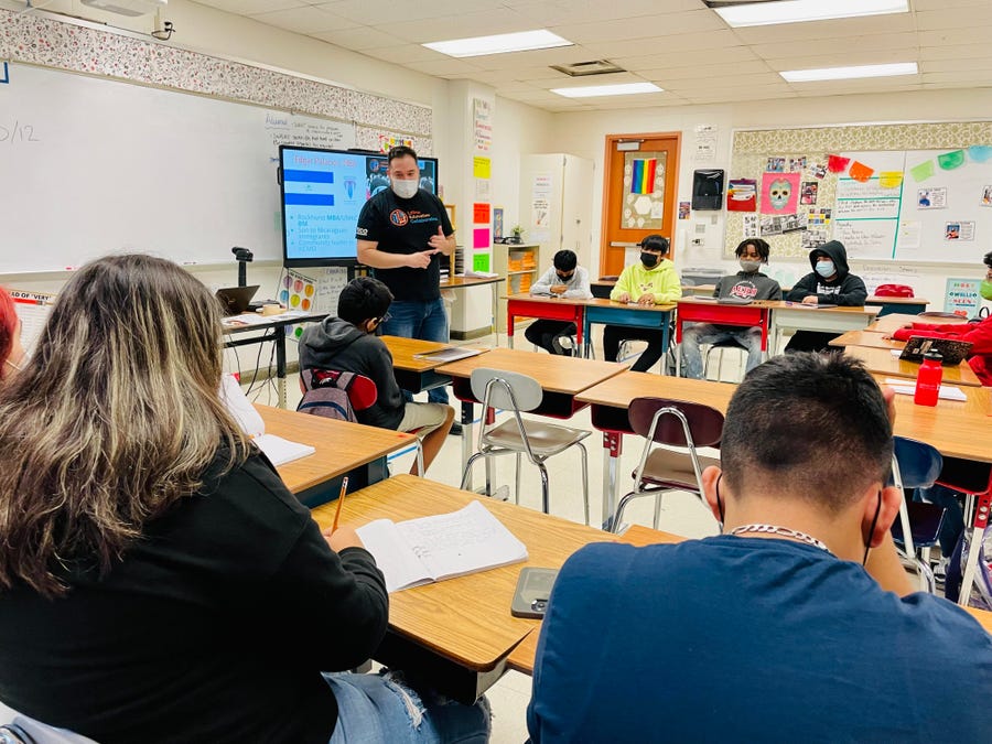 Edgar Palacios stands in front of a classroom.