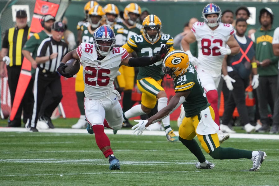 Giants running back Saquon Barkley carries the ball during the second quarter as Packers safety Adrian Amos (31) tries to make a tackle during their game at Tottenham Hotspur Stadium in London on Oct. 9.