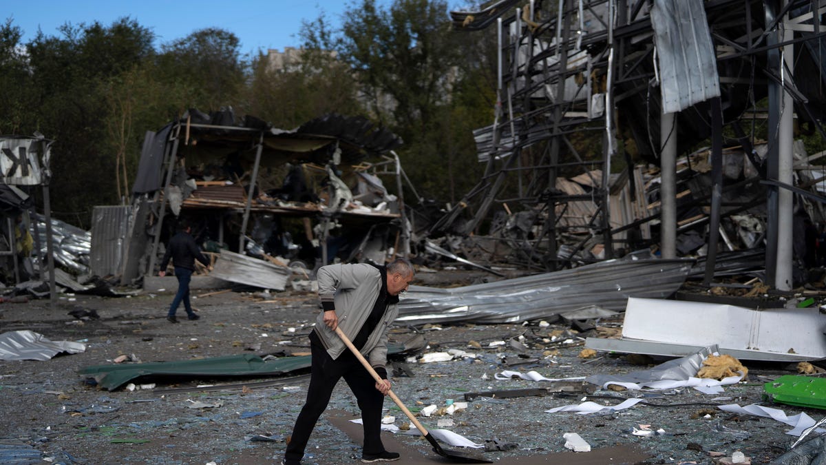 An employee cleans the debris at the remains of a car shop that was destroyed after a Russian attack in Zaporizhzhia, Ukraine, Tuesday, Oct. 11, 2022.