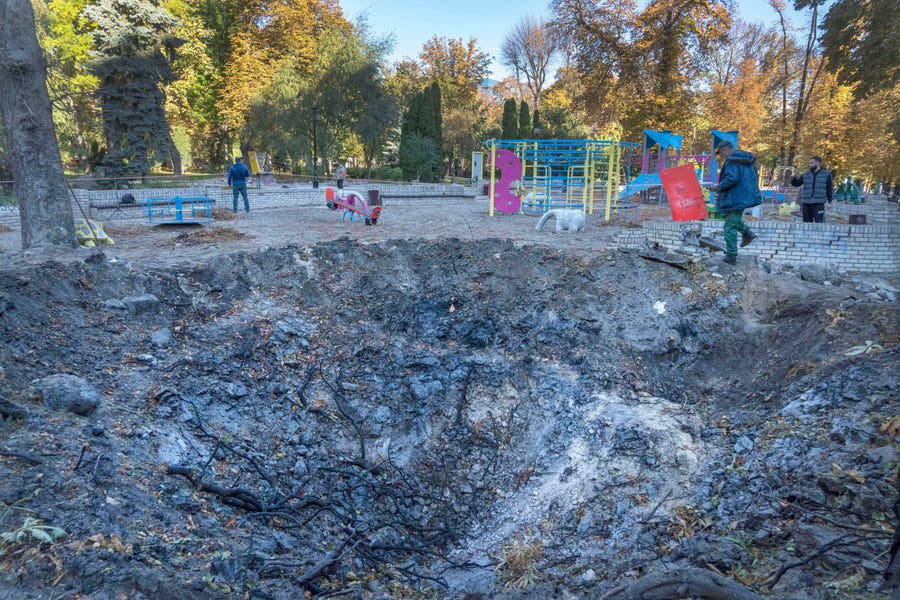 A man passes past a rocket crater at playground in city park in center Kyiv, Ukraine, Tuesday, Oct. 11, 2022. Russia on Monday retaliated for an attack on a critical bridge by unleashing its most widespread strikes against Ukraine in months.