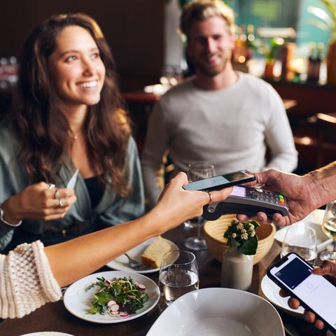 Friends paying contactlessly in restaurant