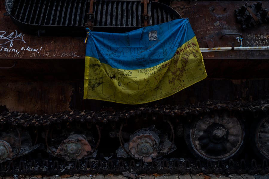 A Ukrainian flag with messages of support for cities of eastern Ukraine hangs from a destroyed Russian tank displayed in downtown Kyiv on Nov. 7, 2022.