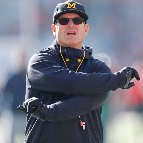 Michigan coach Jim Harbaugh warms up before his te